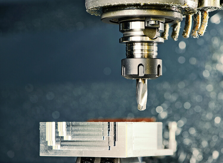 Kopf von CNC Fräsmaschine, darunter Werkstück.